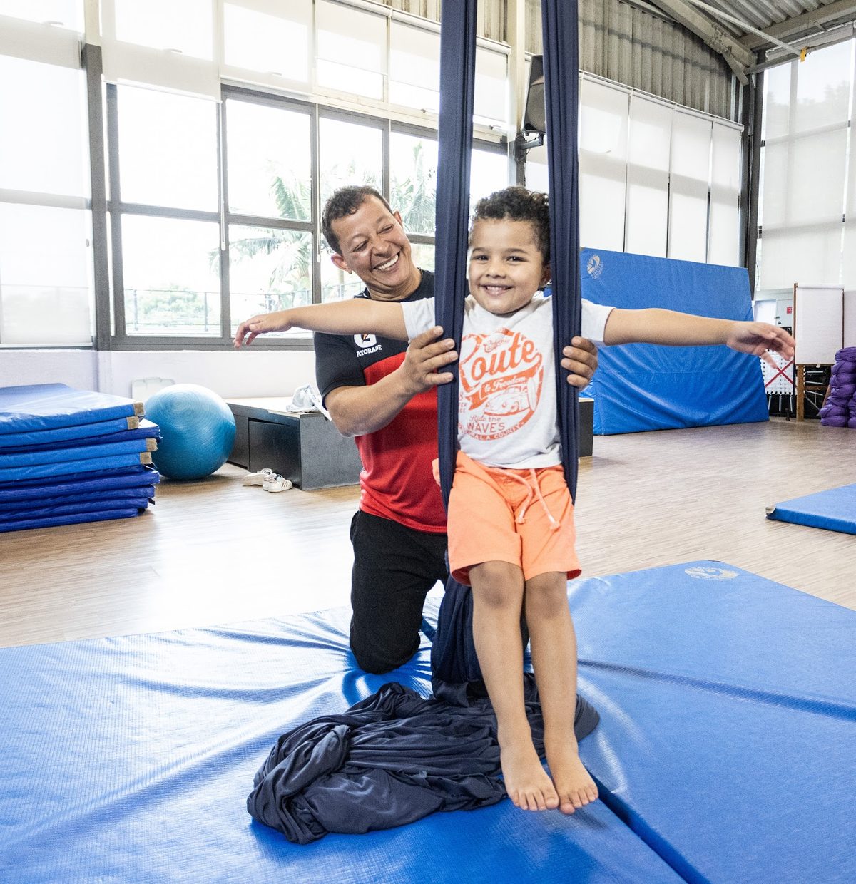 Professor da unidade Kansas apoiando uma criança em uma atividade de tecido acrobático
